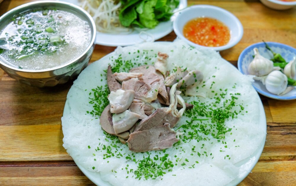 A complete serving features a plate of soft, thin rice sheets brushed with fragrant chives, a platte...