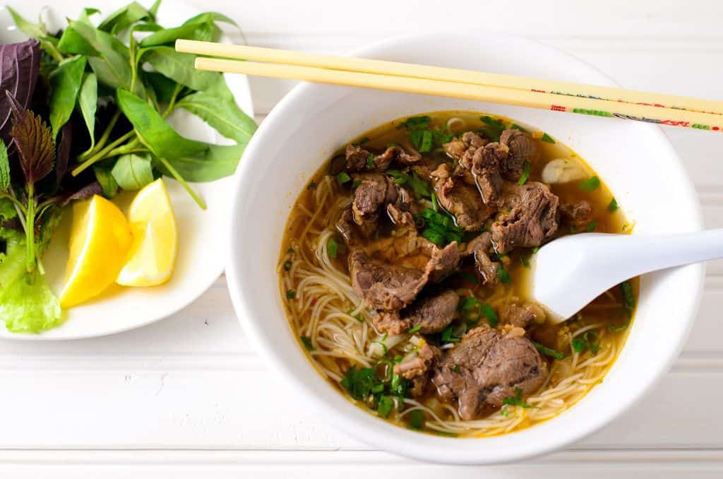 What defines authentic Bún Bò Huế is its thick, chewy noodles from Vân Cù, crystal-clear broth sweet...