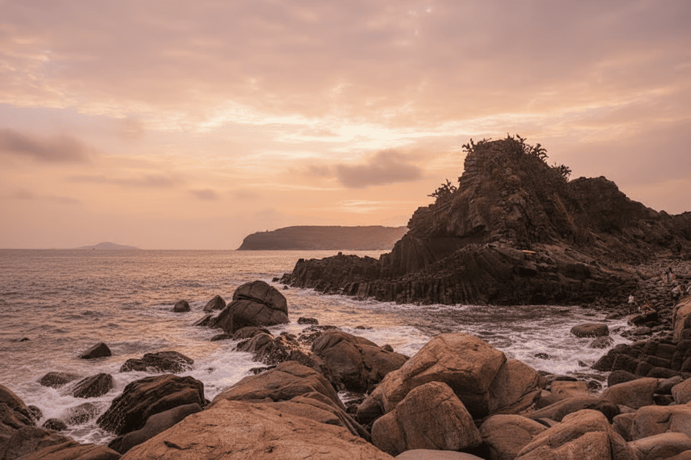In front of the rock formations lies a breathtaking pristine beach, with crystal-clear waters and ge...