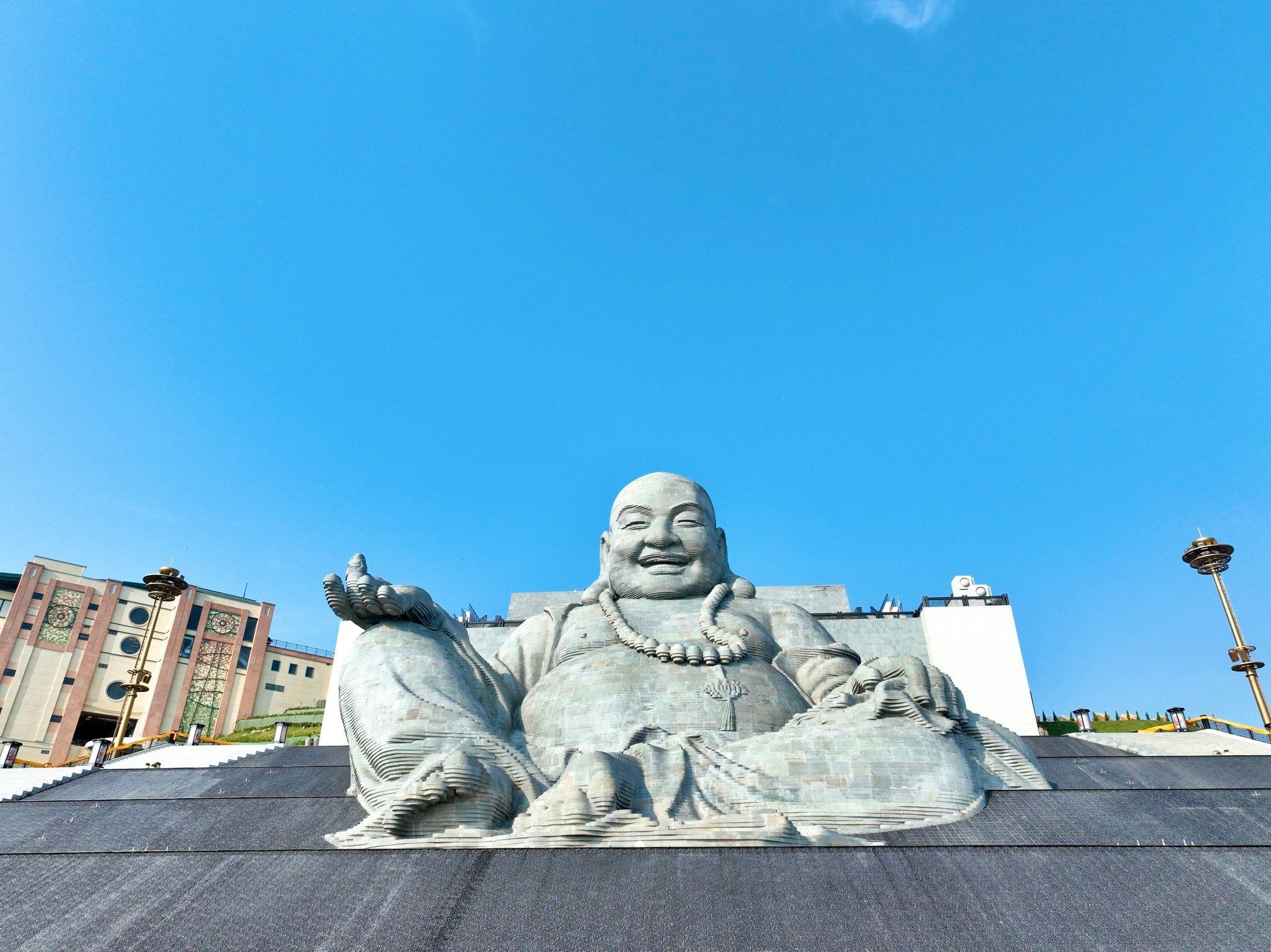 Not far from the Buddha, the Statue of Maitreya Bodhisattva is seated serenely on a majestic waterfa...